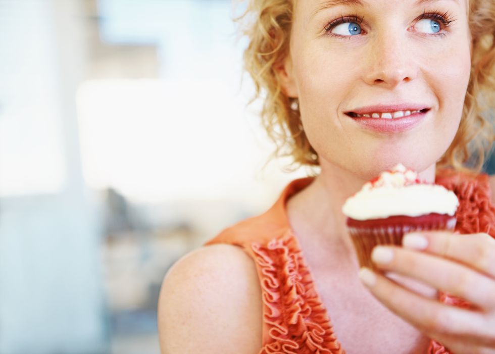 woman holding a cupcake and looking away happily