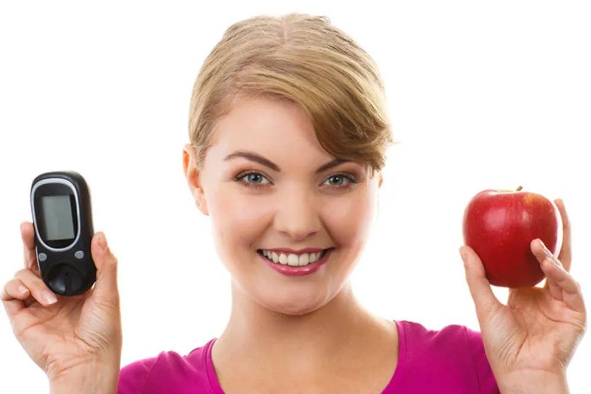 woman holding a diabetes tester and an apple