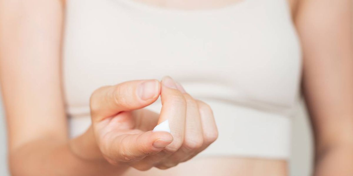 Woman holding a drop of white moisturizing cream on her finger