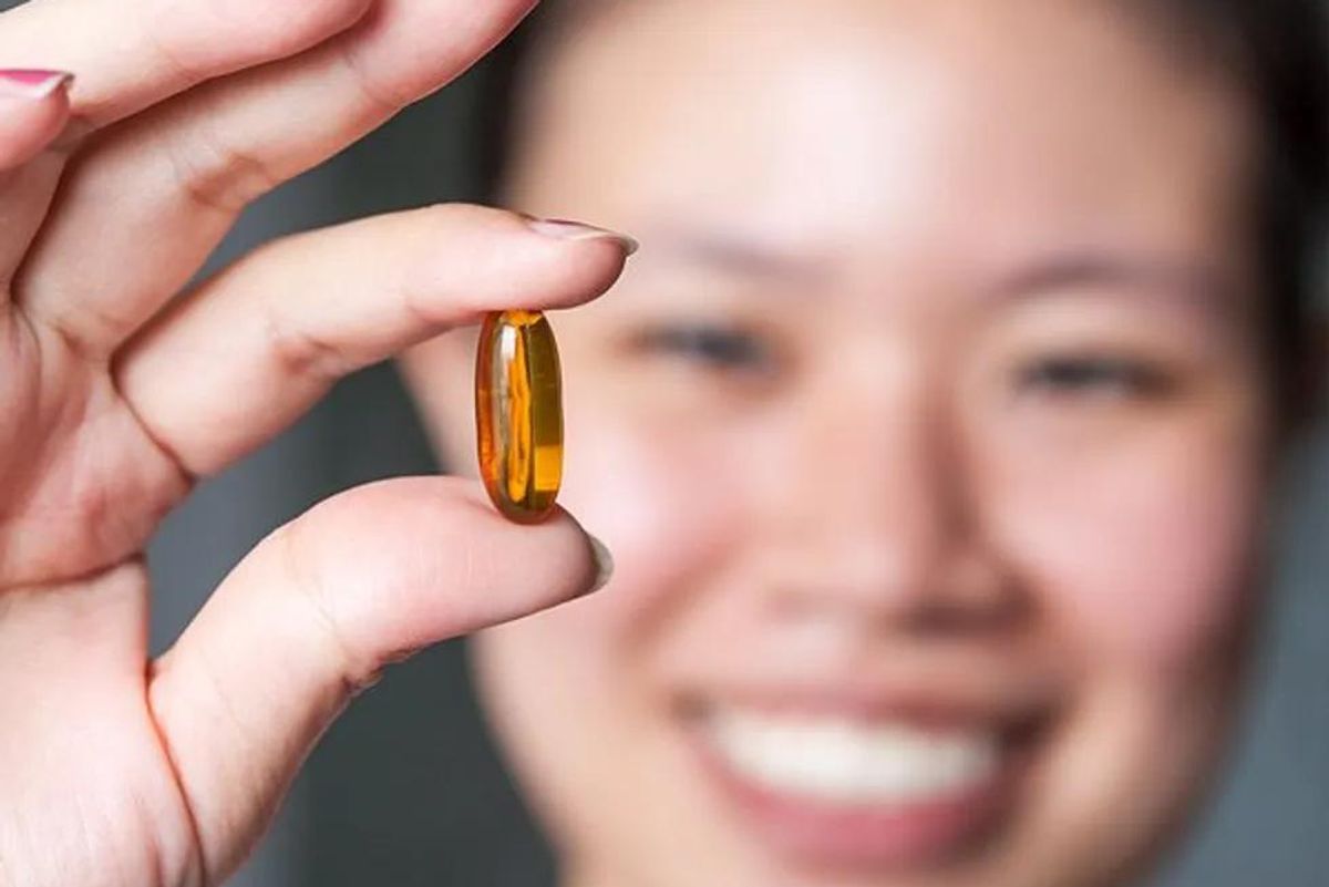 woman holding a fish oil pill