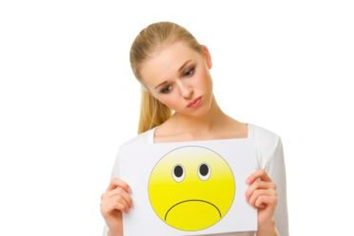 woman holding a sad face sign