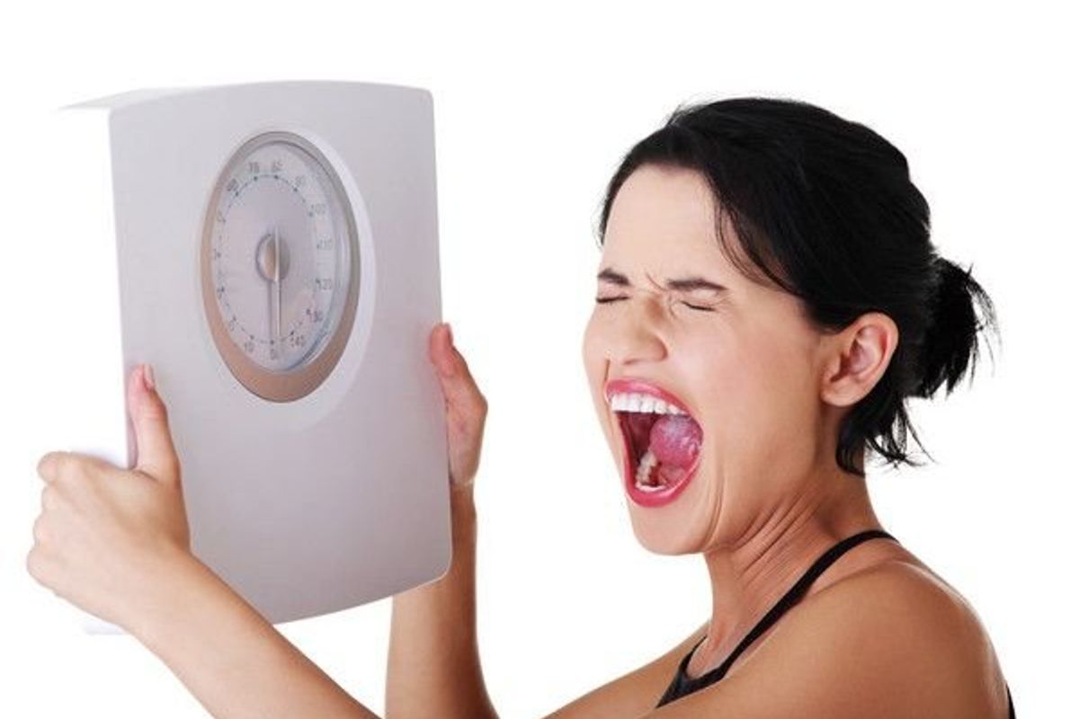 woman holding a scale and screaming
