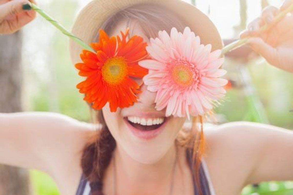 woman holding daisies in front of her face