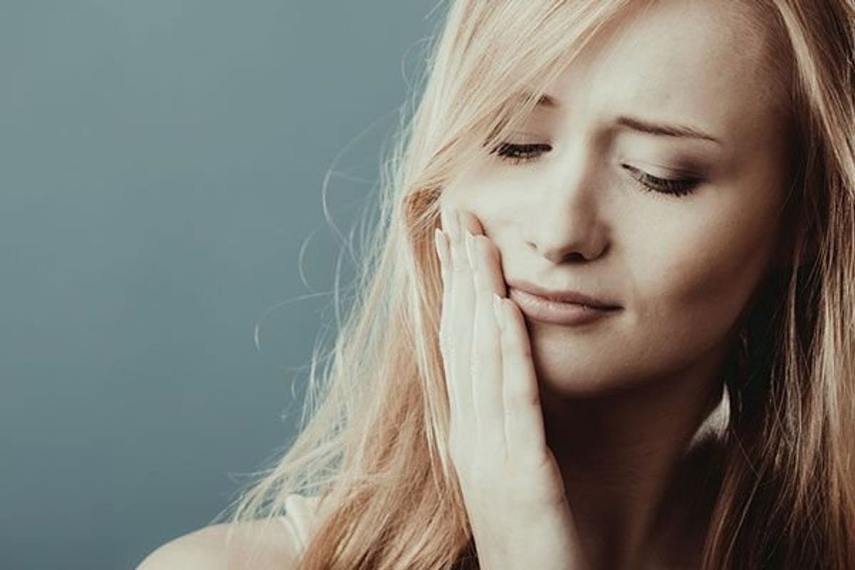 woman holding her jaw in pain