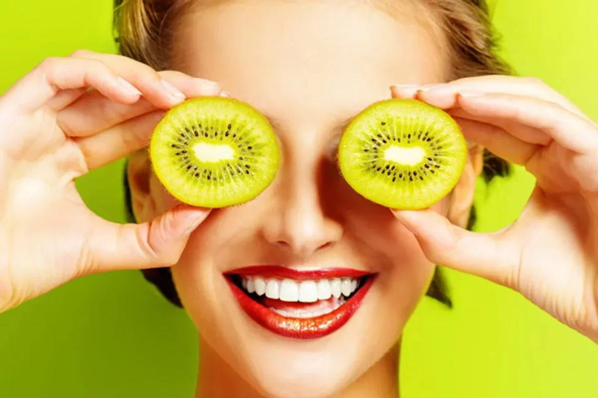 woman holding kiwis in front of her eyes