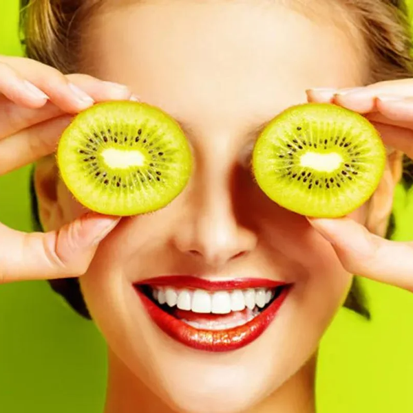woman holding kiwis in front of her eyes