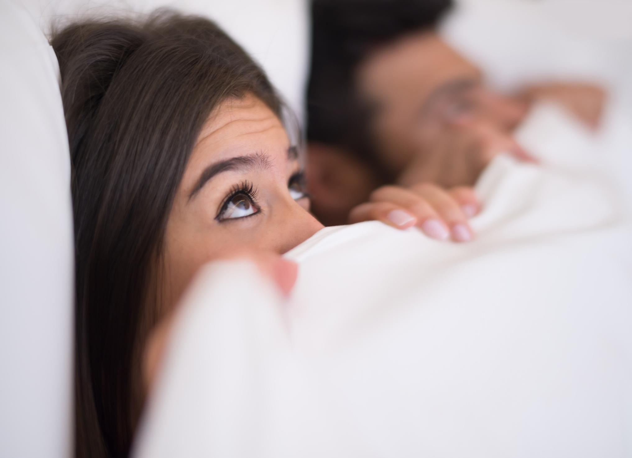 woman in bed with a man looking very anxious