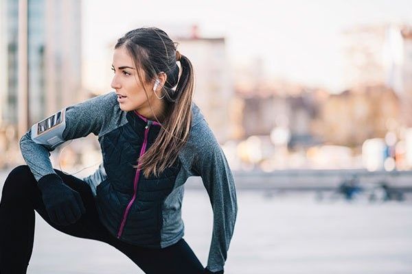 woman in sports wear stretching outdoors at urban scene