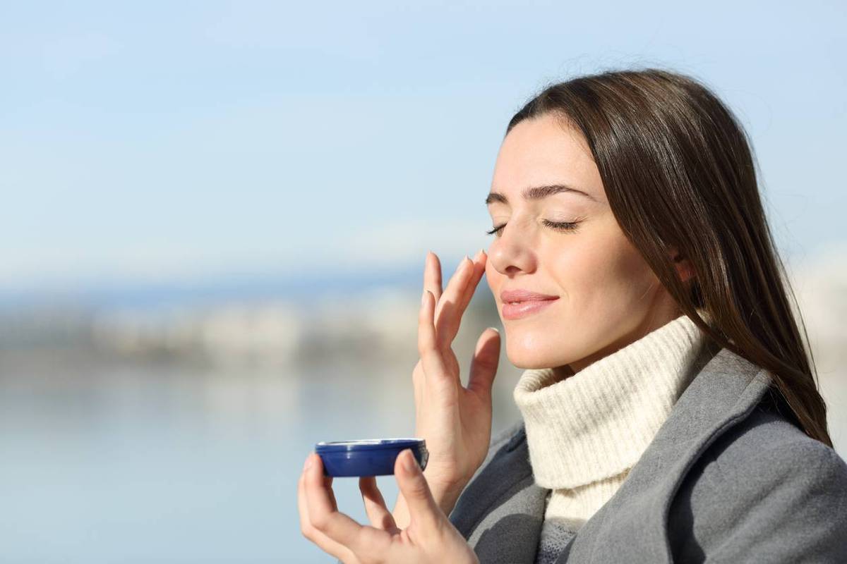 woman in winter applying moisturizer cream