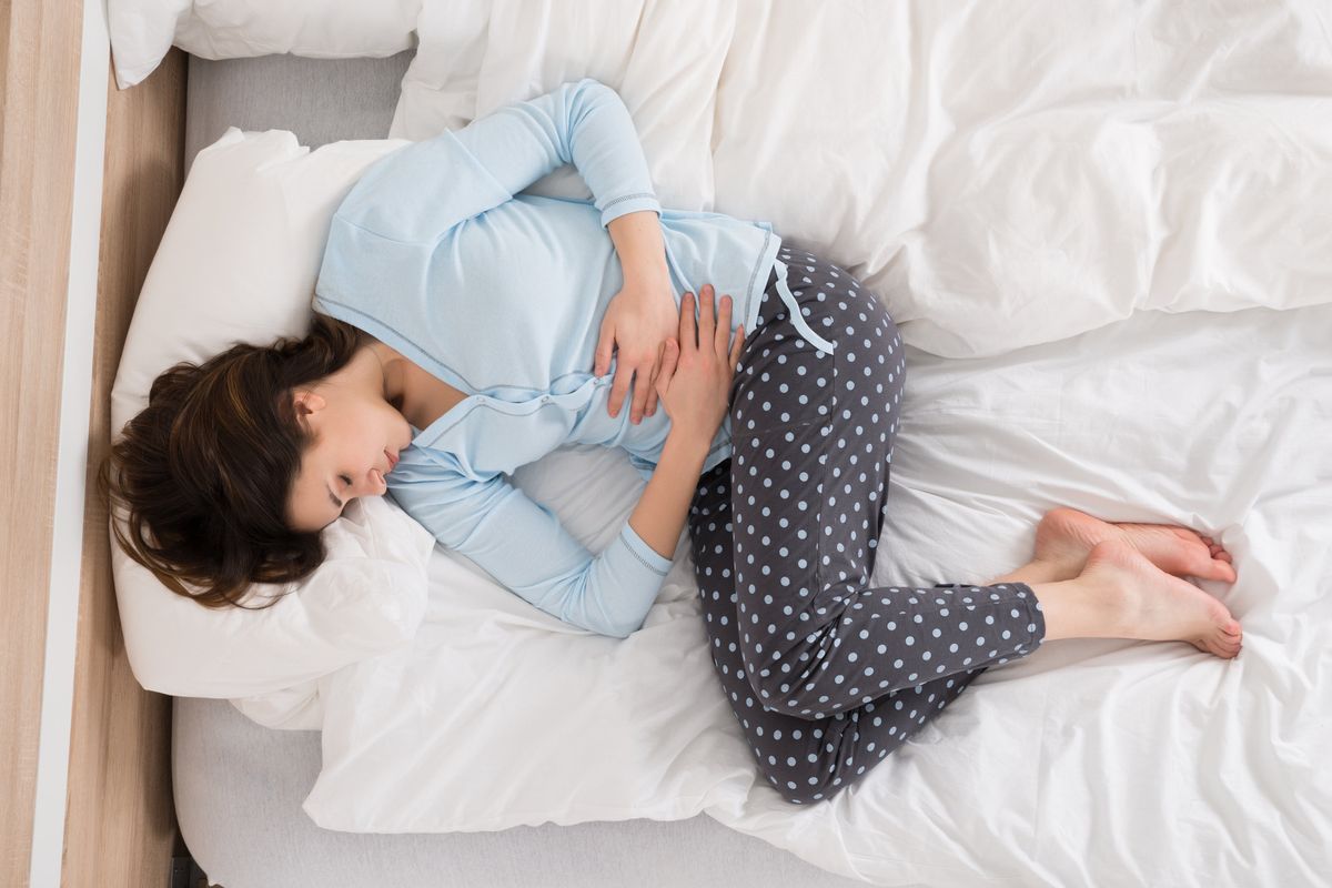 woman laying in her bed with pelvic pain