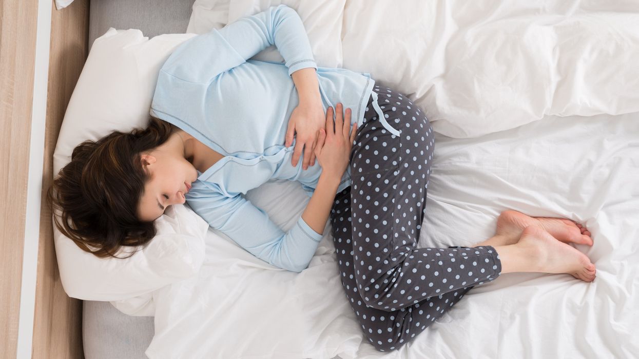 woman laying in her bed with pelvic pain