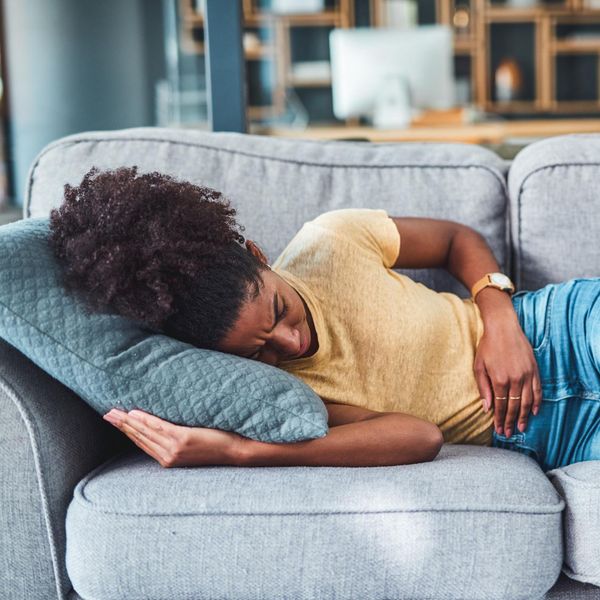 woman laying on the couch due to pain from Heavy Periods