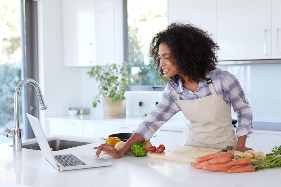 woman looking at an online recipe on her tablet while preparing a meal for weight loss