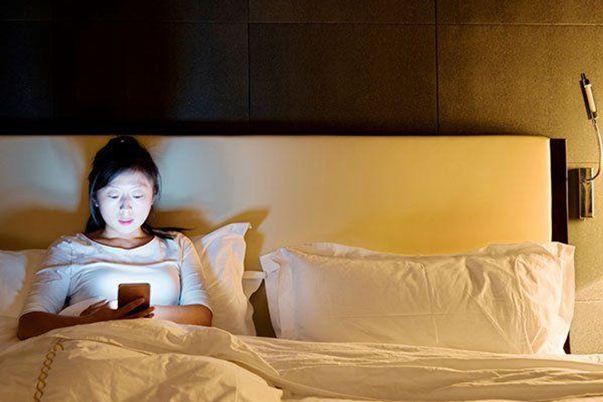 woman looking at her smartphone in bed