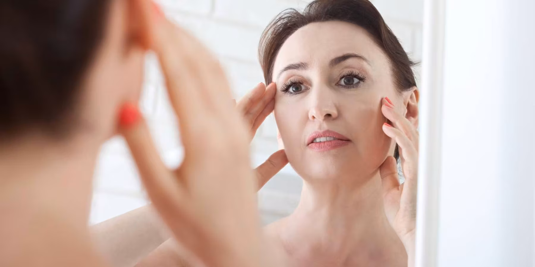 Woman looking at wrinkles in mirror