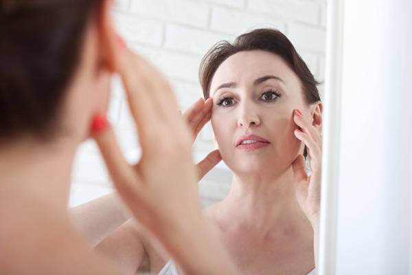 Woman looking at wrinkles in mirror