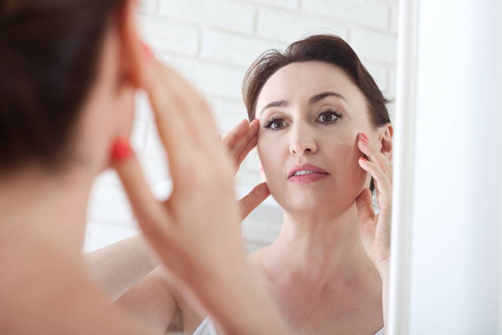 woman looking at wrinkles in mirror