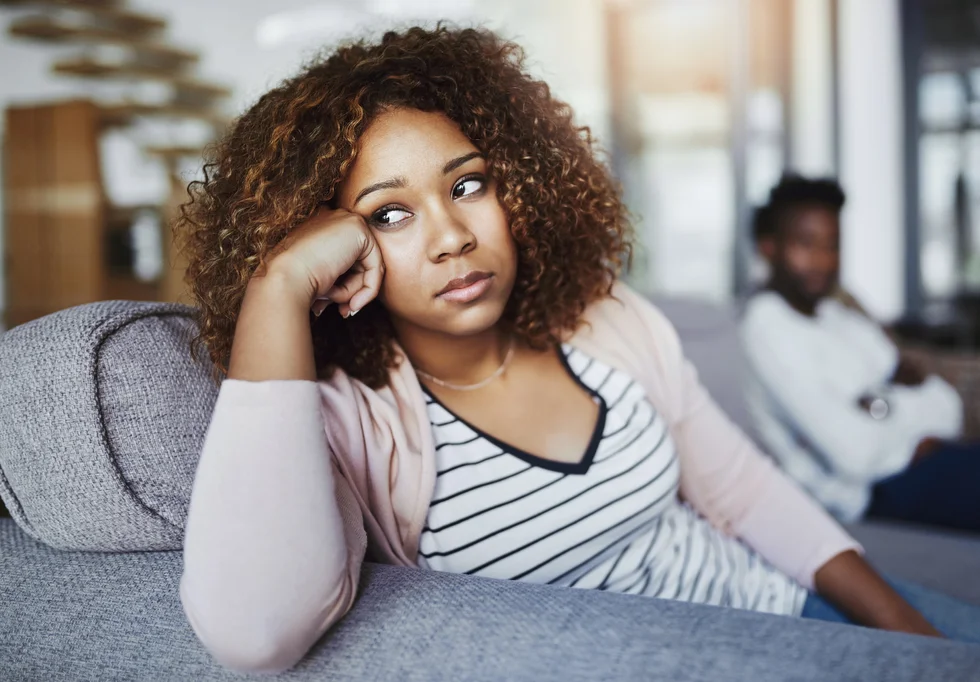 woman looking despondent, sitting on her couch