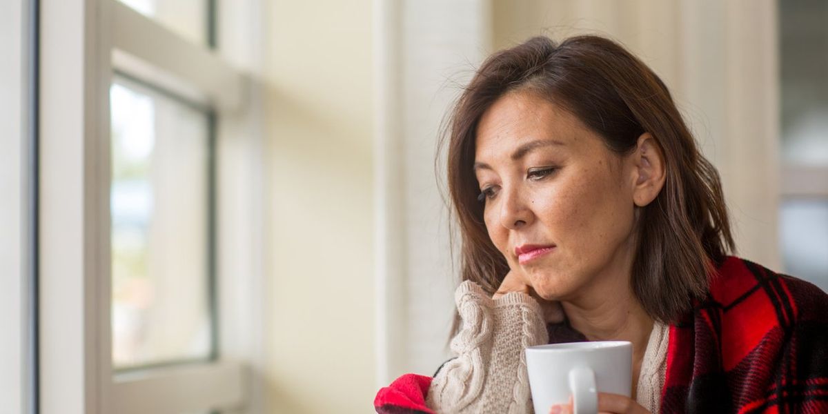woman looking out the window feeling sad