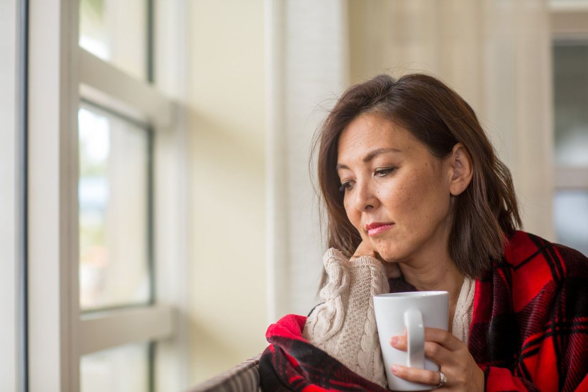 woman looking out the window feeling sad