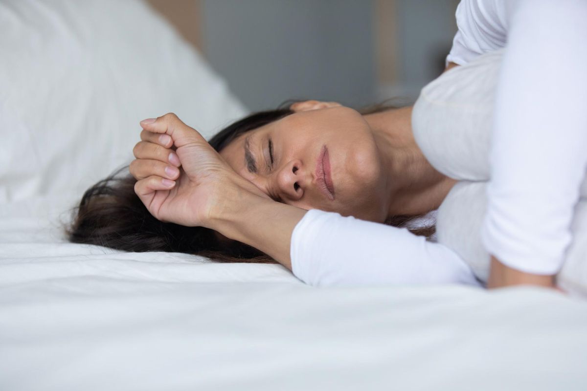 Woman lying in bed in pain with her eyes closed