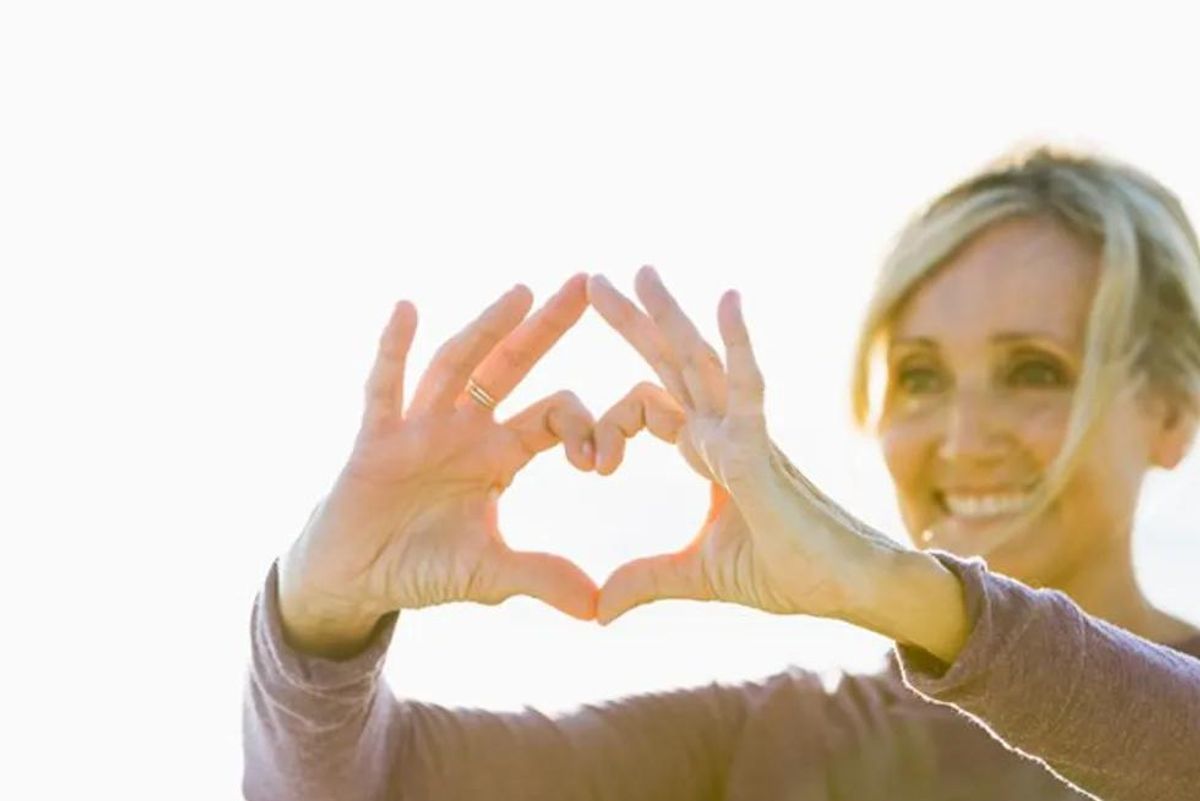 woman making the shape of a heart with her hands