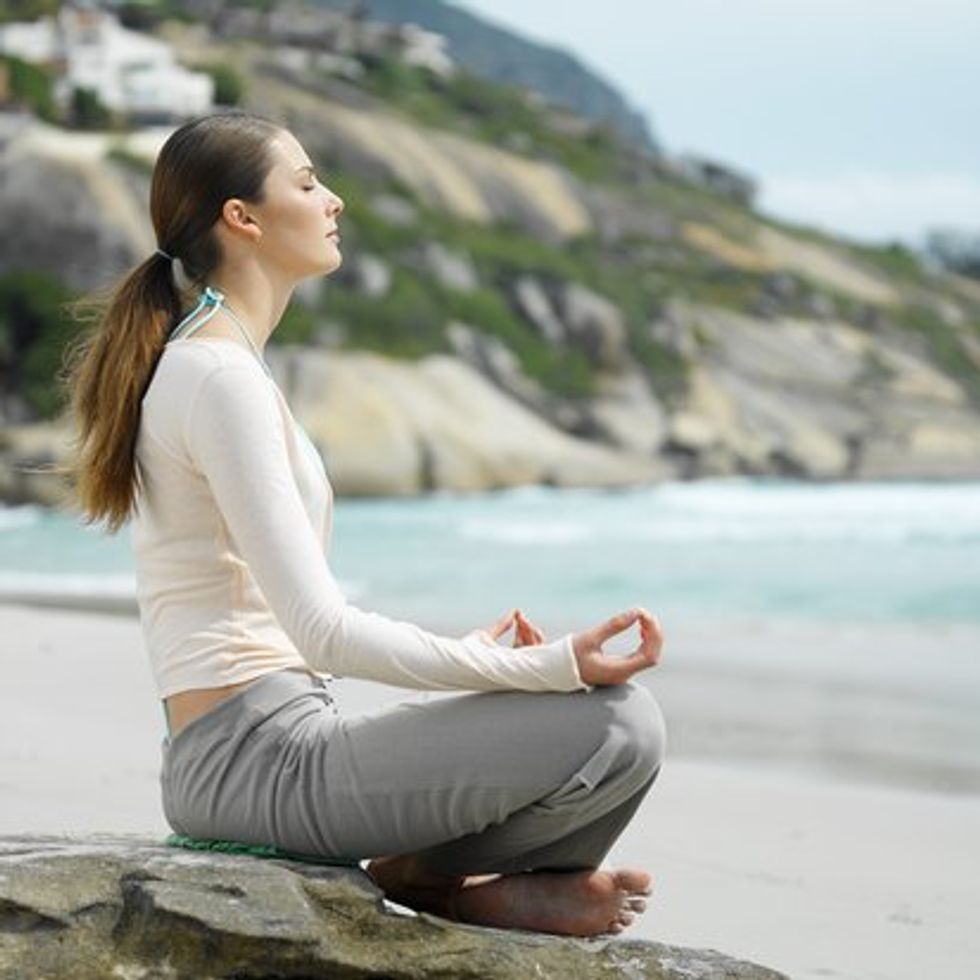 woman meditating by the beach