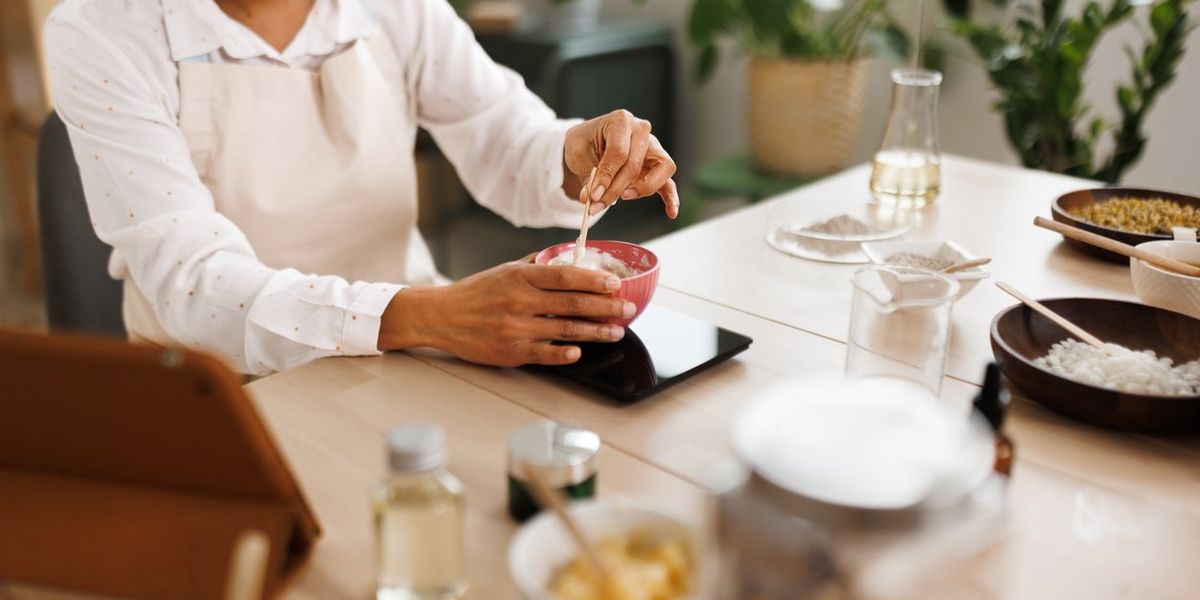 Woman mixing ingredients for homemade hand cream at her workshop