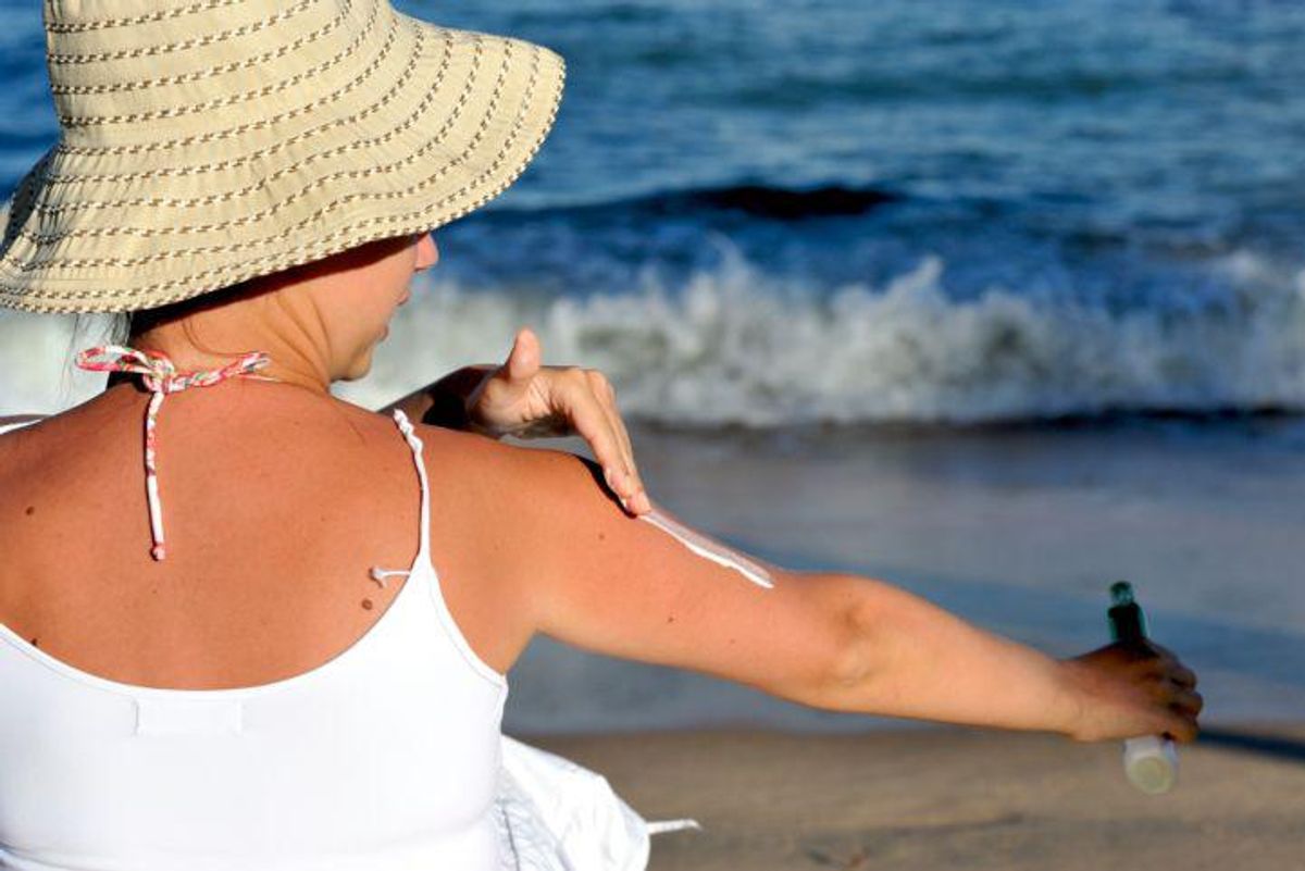 woman on the beach applying sunscreen