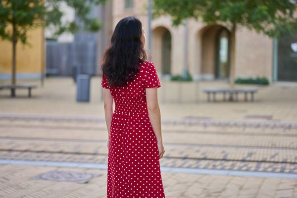 woman outdoors in the city wearing red dress full length portrait rear view.