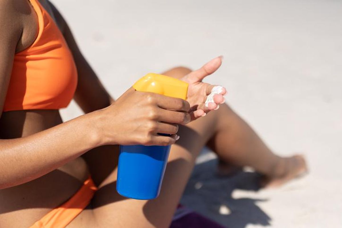 woman putting sunscreen on the beach