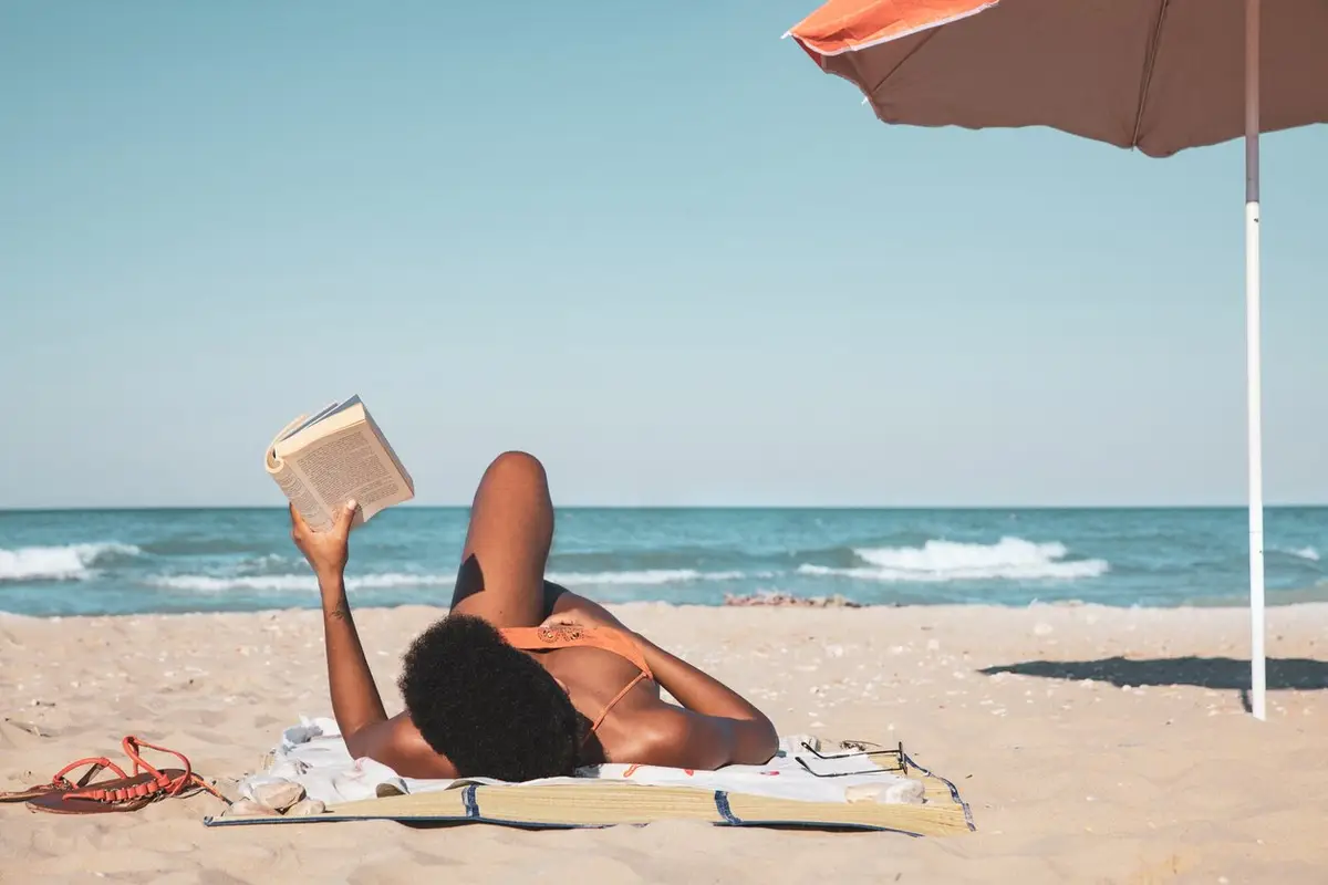 woman reading a book and relaxing on the beach