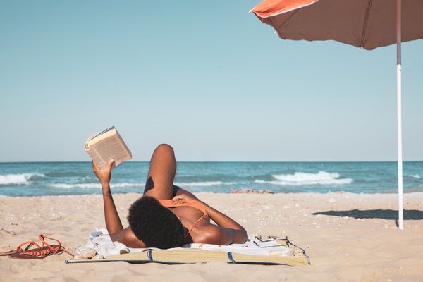 woman reading a book and relaxing on the beach