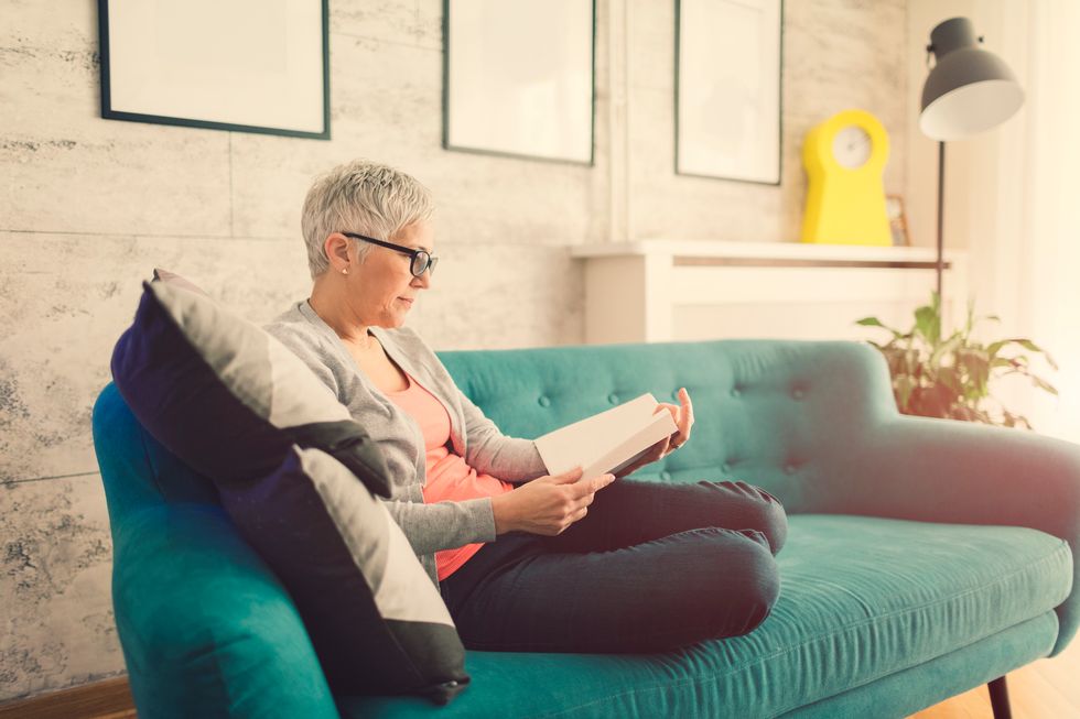 woman reading book on sofa at home