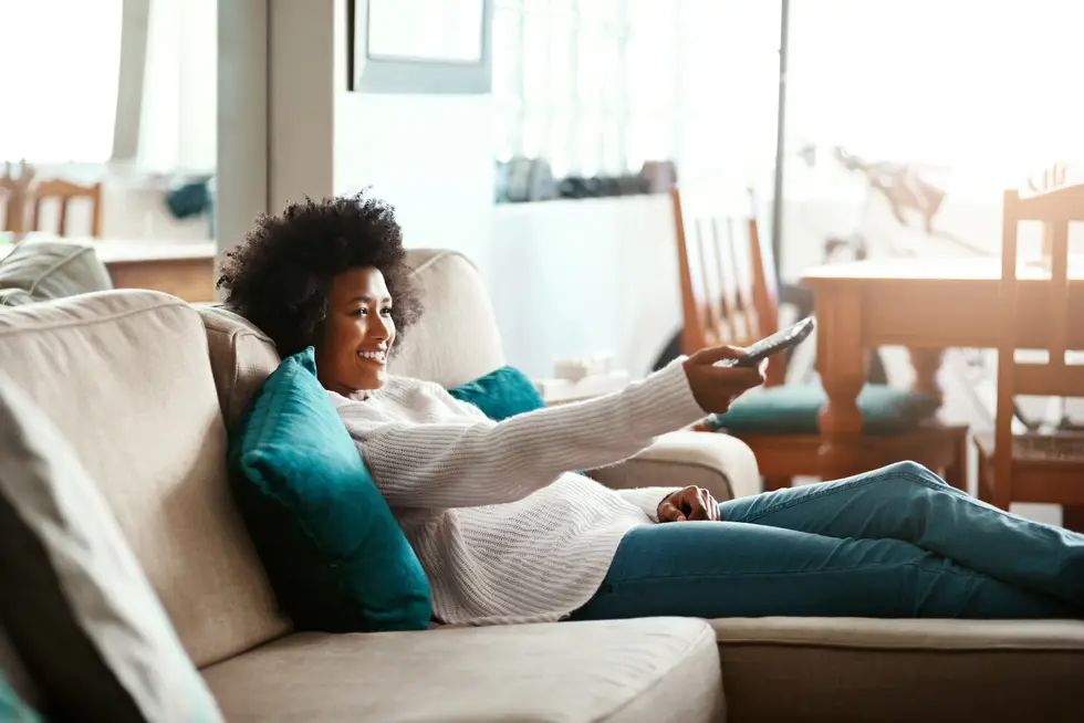 woman relaxing on the sofa at home and watching tv to Manage Stress