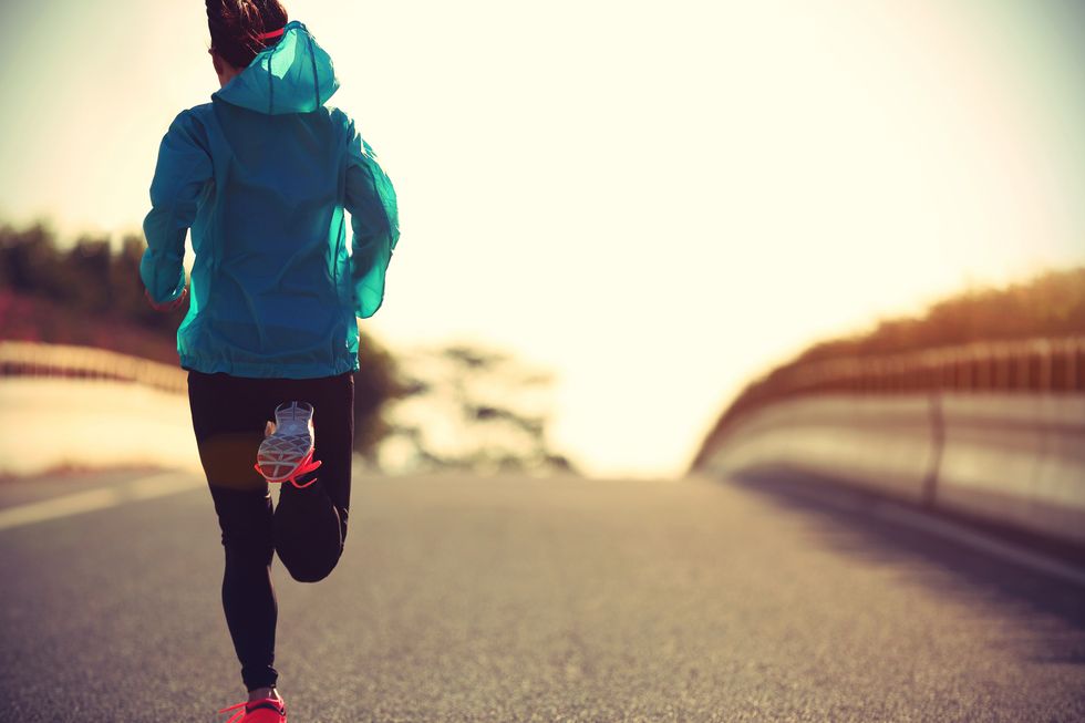 woman runner running on sunrise road