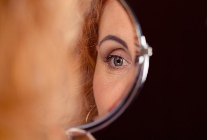 woman's eye reflected in a round small mirror