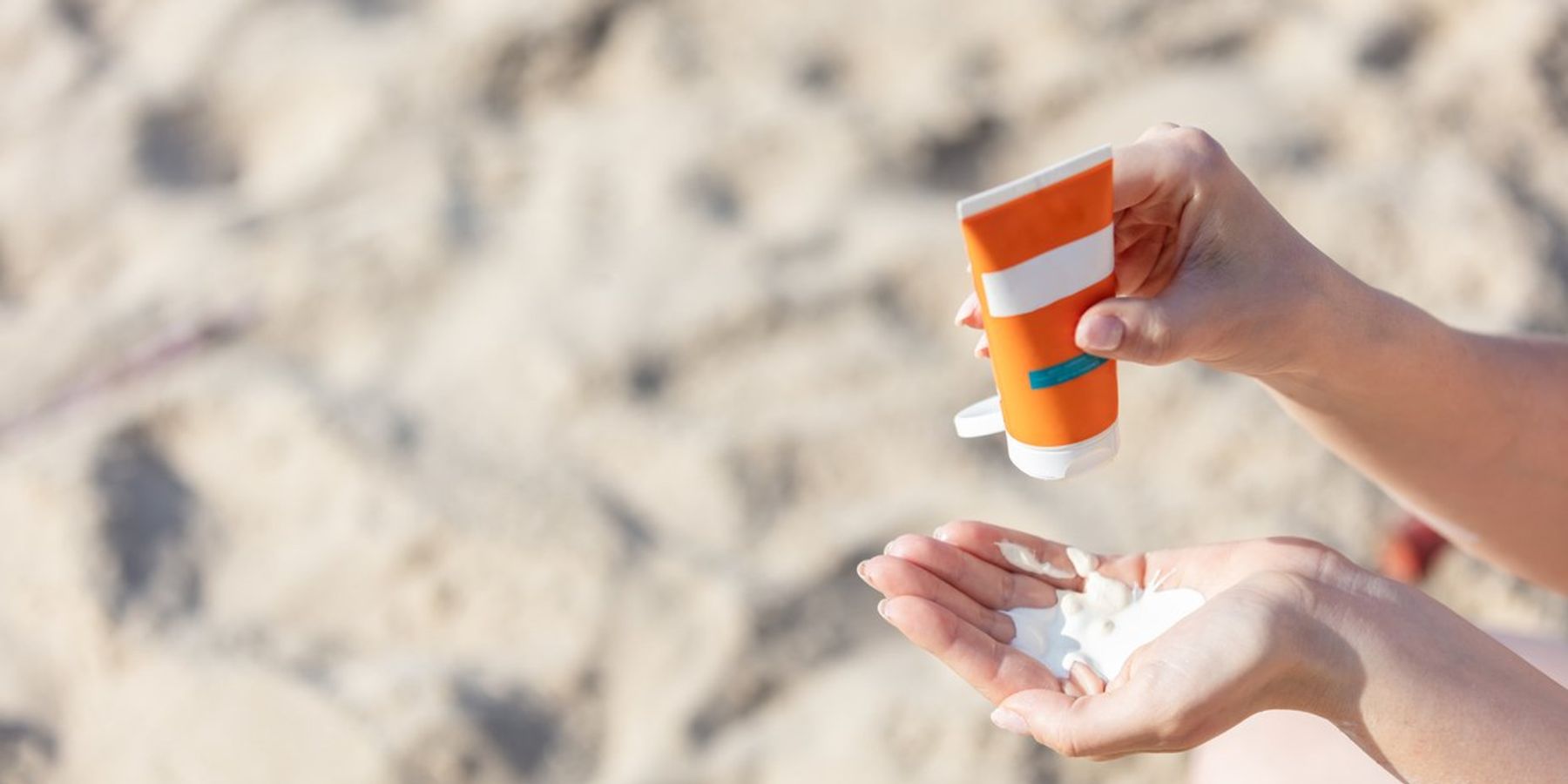 Woman's hand squirting sunscreen lotion