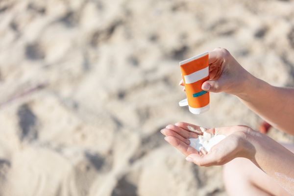 Woman's hand squirting sunscreen lotion