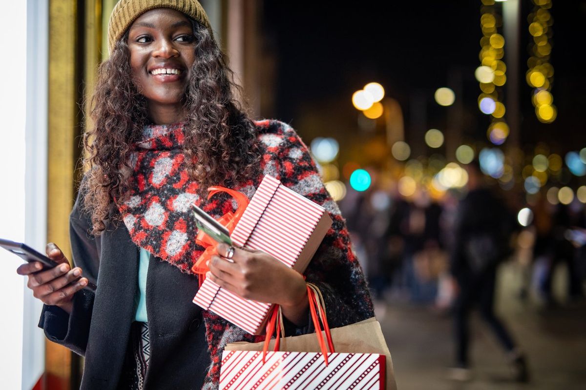 woman shoppinh online and holds gifts in her hand
