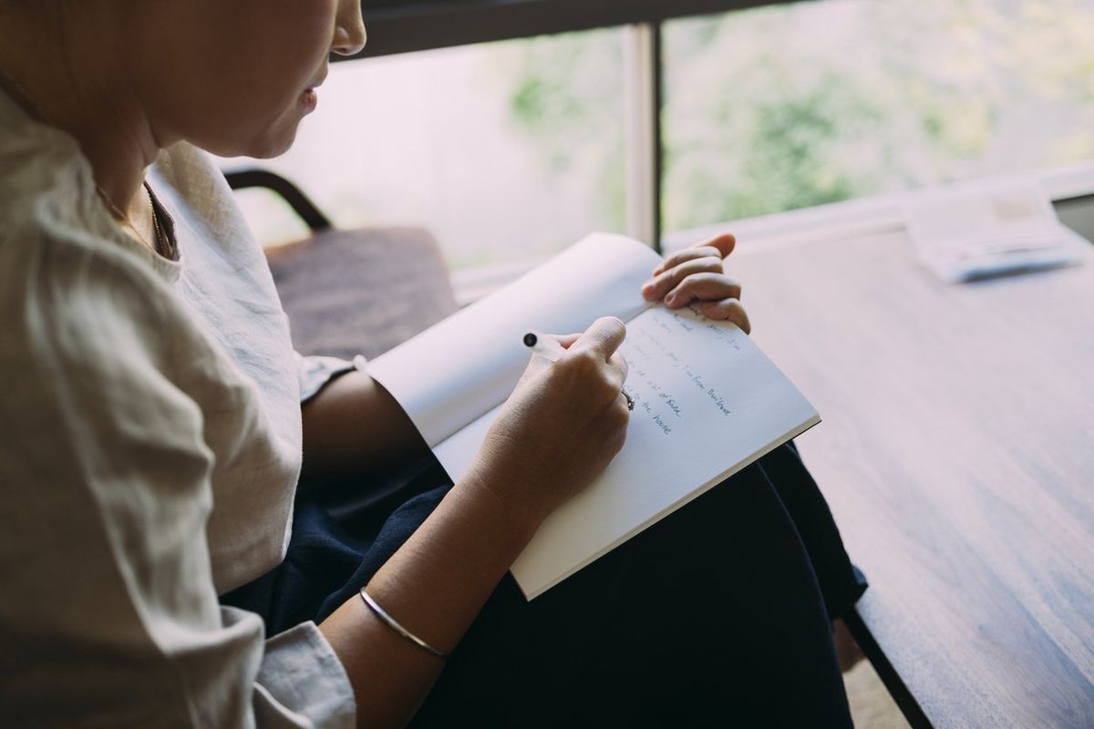 woman sitting in her living room, writing in her notebook