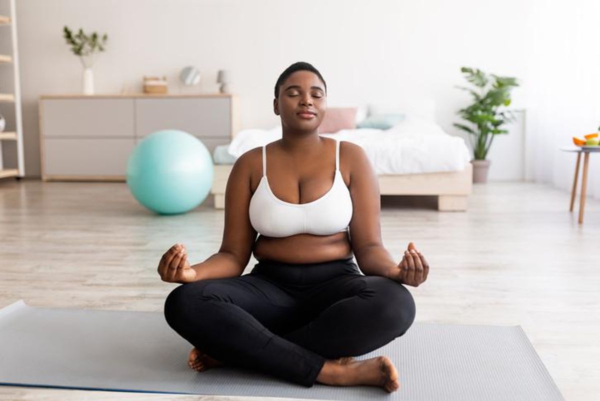 woman sitting in lotus pose, meditating with closed eyes