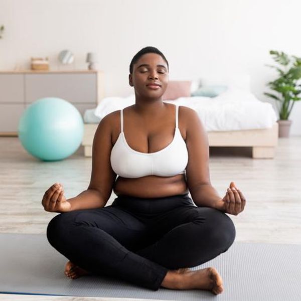 woman sitting in lotus pose, meditating with closed eyes