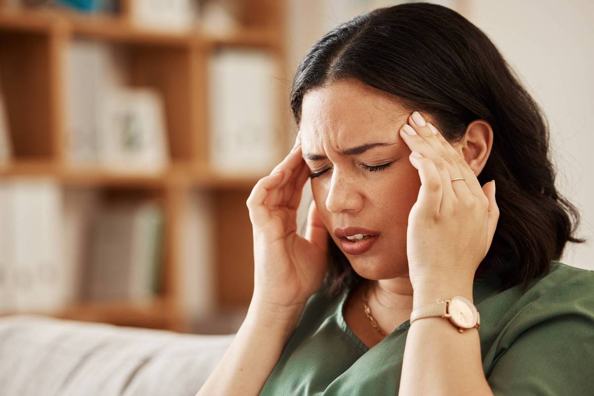 woman sitting on couch wtih a bad headache