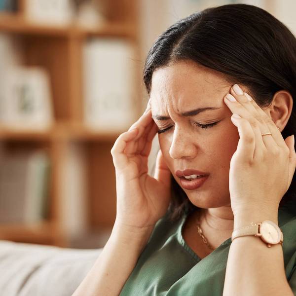 woman sitting on couch wtih a bad headache