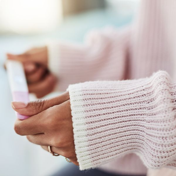 woman sitting on her bed alone and waiting for a pregnancy test result at home