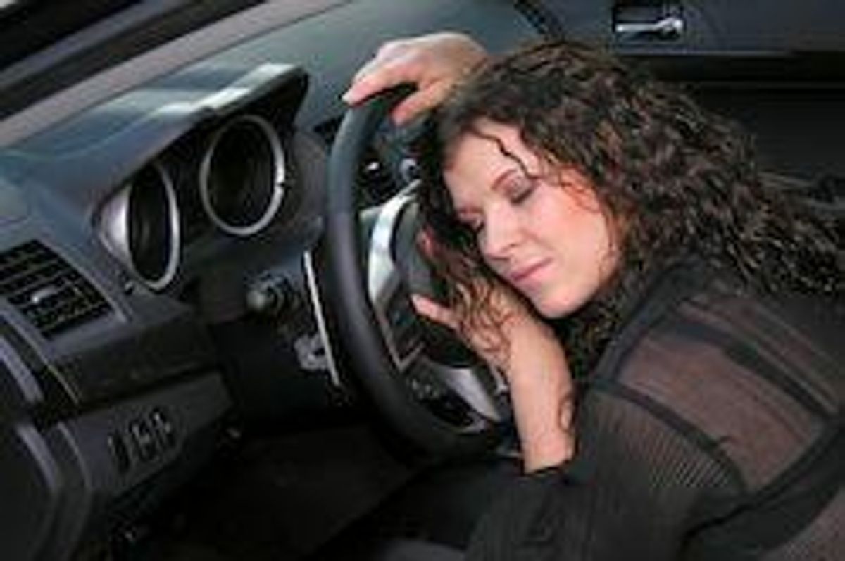 woman sleeping on the steering wheel of a car
