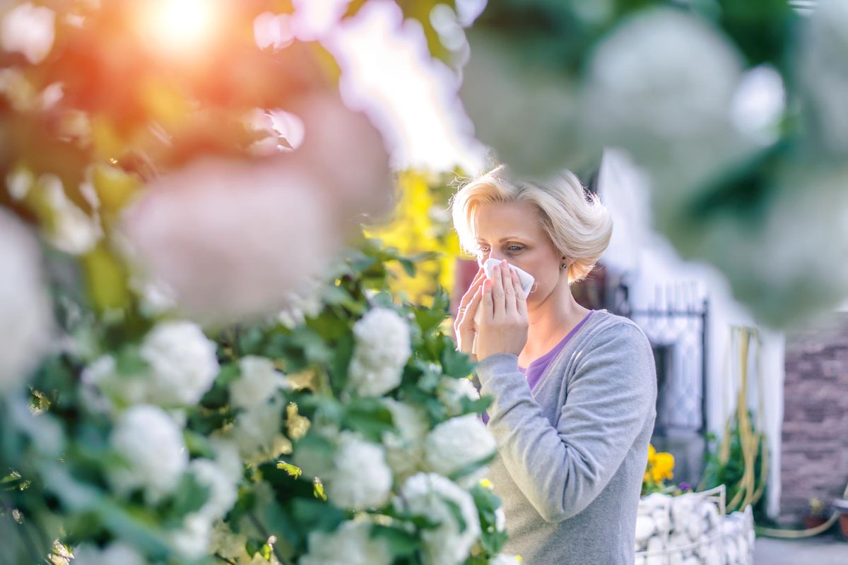 Woman sneezing in the blossoming garden