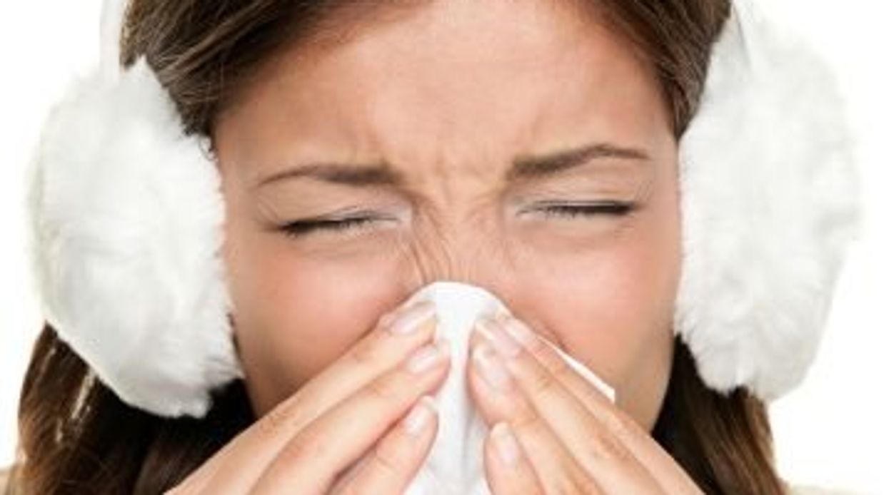 woman sneezing while wearing ear muffs