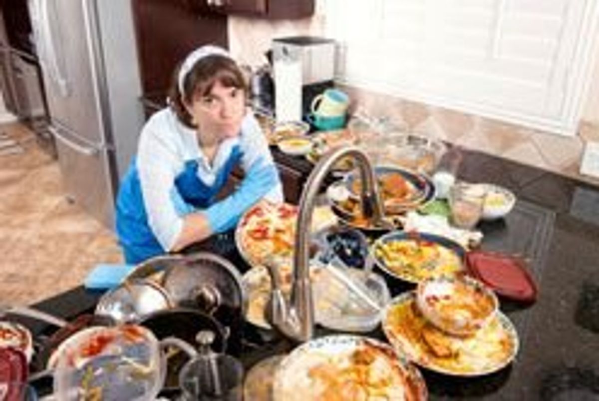 woman standing over a sink full of dirty dishes